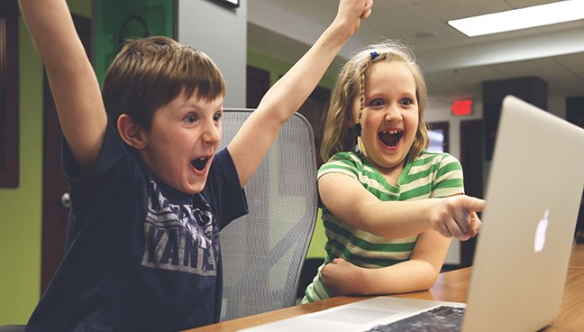 Two children watching something on a MacBook